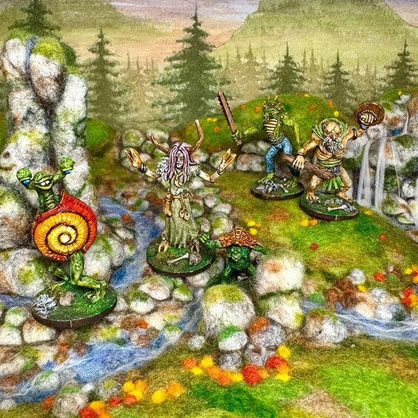 Miniature figurines from Trish Carden HarrowHyrst range in a fantasy landscape with mountains and trees.