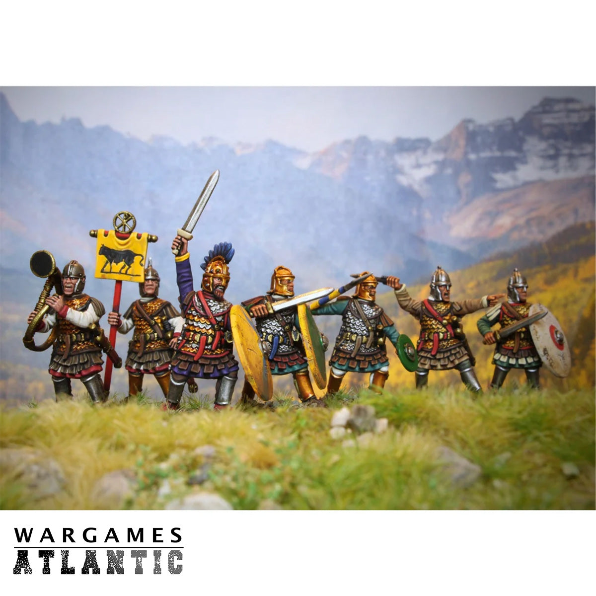 A group of painted tabletop wargaming miniature soldiers in medieval armor standing in a grassy mountain landscape. The figures include shields, swords, spears, and a yellow banner.