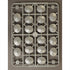 A rectangular gray plastic sprue holding multiple Roman shields, photographed from above on a plain taupe background.