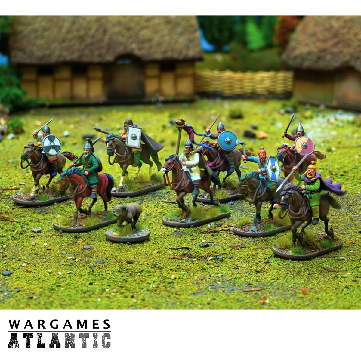A group of painted tabletop wargame miniatures depicting a Viking cavalry unit on a textured green terrain mat, with small thatched-roof huts in the background. The Wargames Atlantic logo is visible at the bottom.