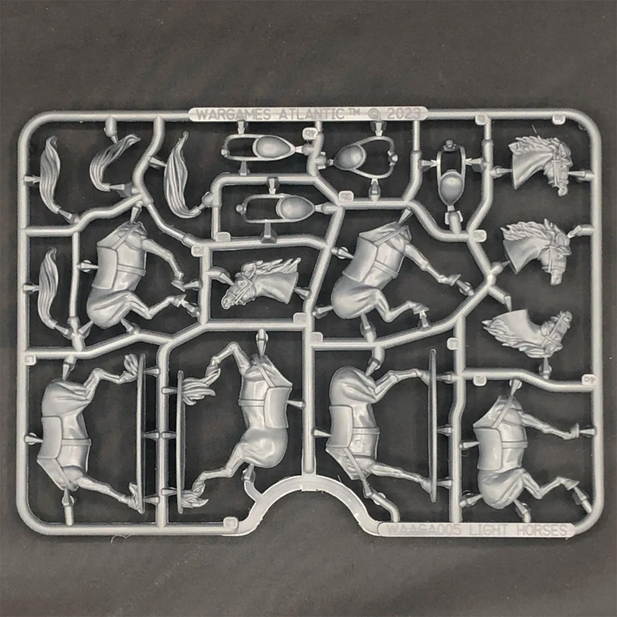 Plastic model kit horses with various pre-assembled parts on a black background